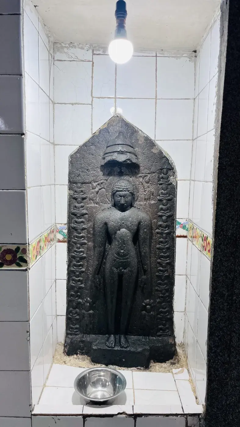 A blue vaulted corridor inside the kshetra, a bell hanging from the ceiling and two doorways opening at the far end.
