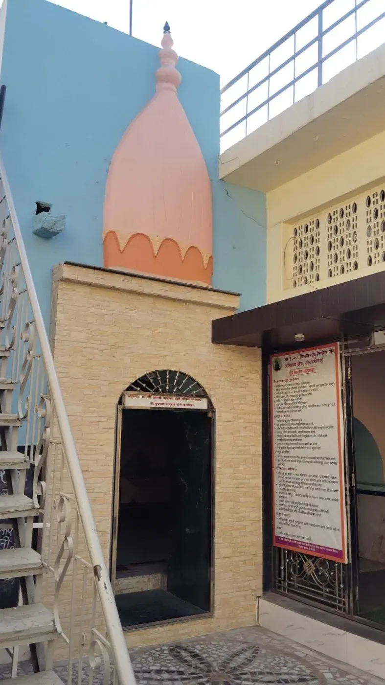 A closer view of the small pink-domed subsidiary shrine and the metal staircase beside it, within the kshetra's inner courtyard.